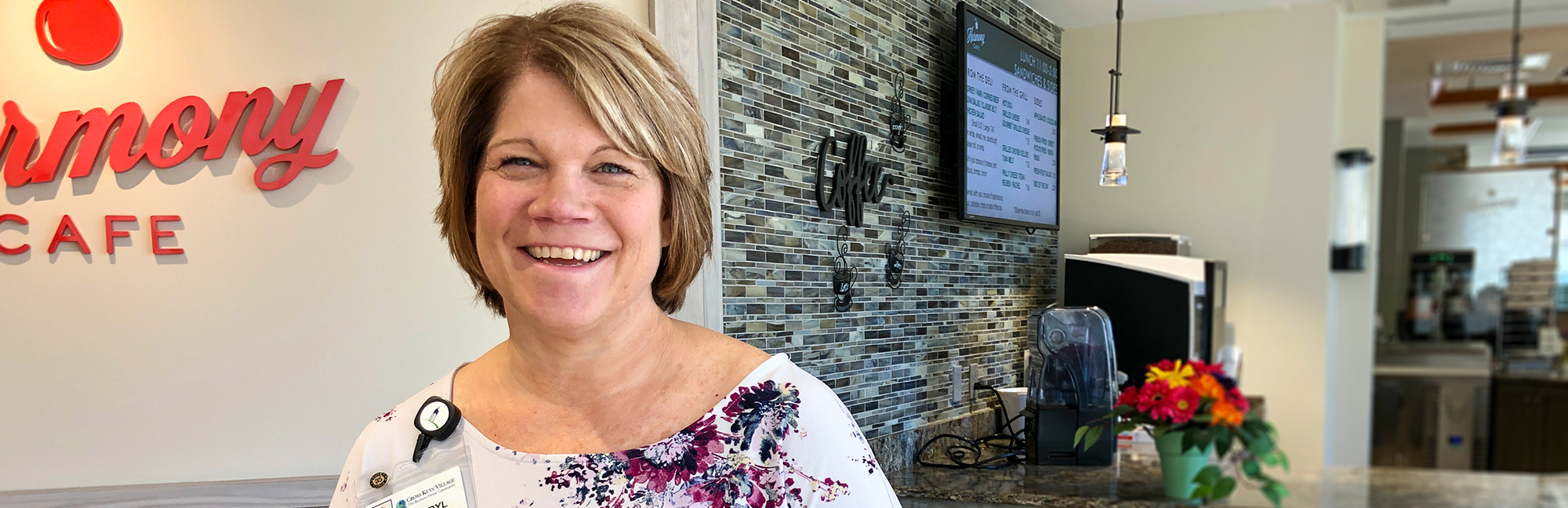 a woman stands in front of a sign that says harmony cafe