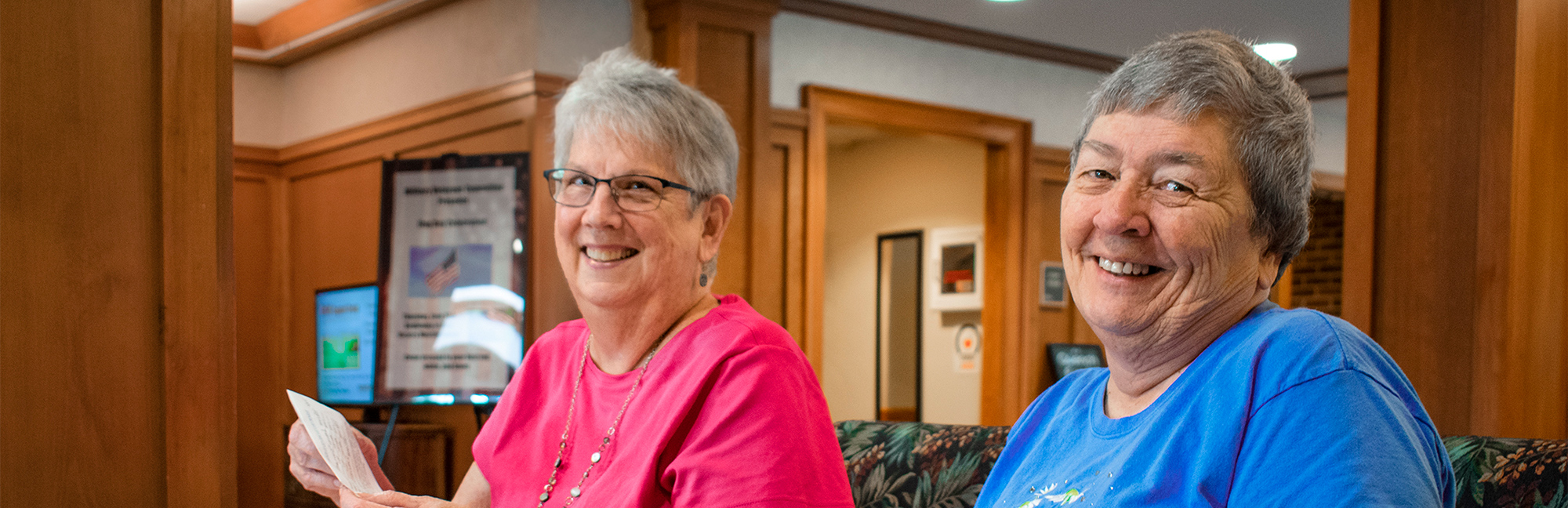 a woman in a blue shirt is smiling next to another woman in a pink shirt