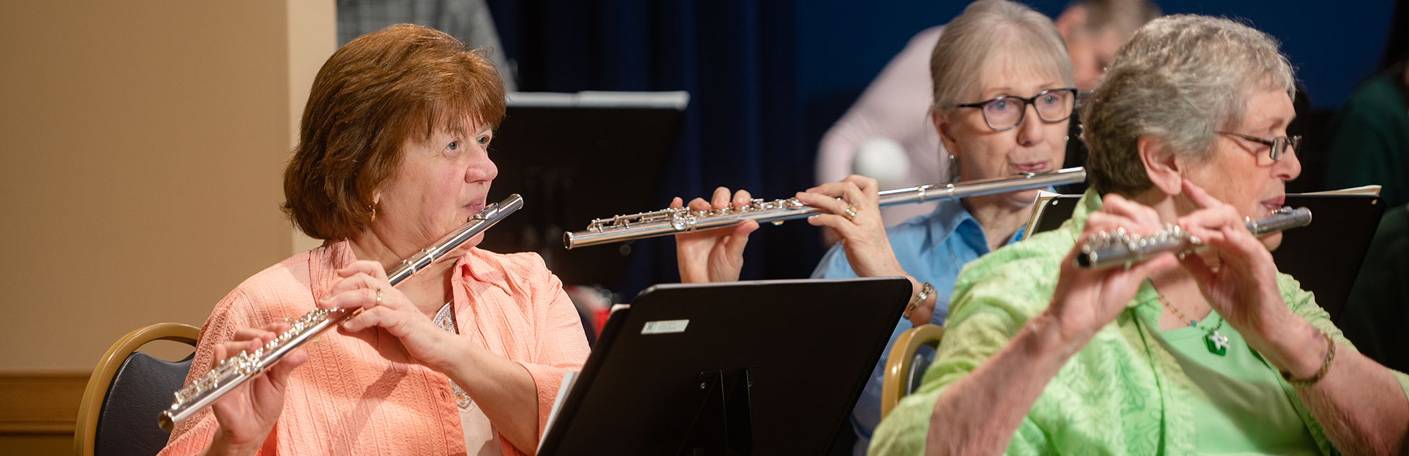 three retired women are playing flutes in an orchestra