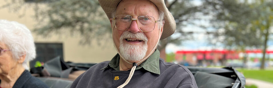 an older man wearing a hat and glasses is smiling