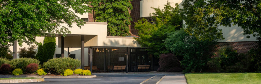 a white building with a brick wall and a covered entrance