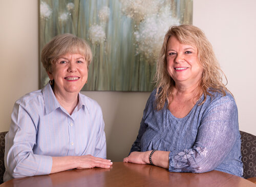 Two ladies sitting at a table together smiling