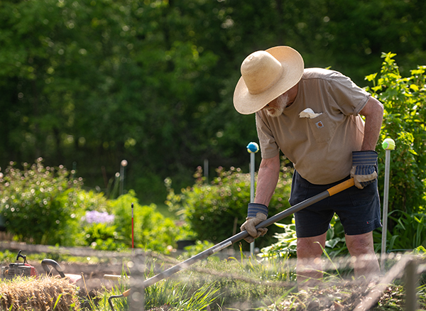 a retired man wearing a straw hat is working in a garden