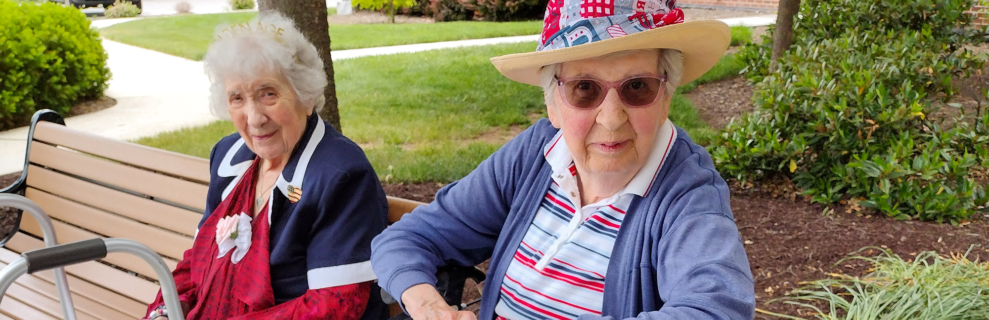 two elderly women sit on a bench wearing patriotic hats
