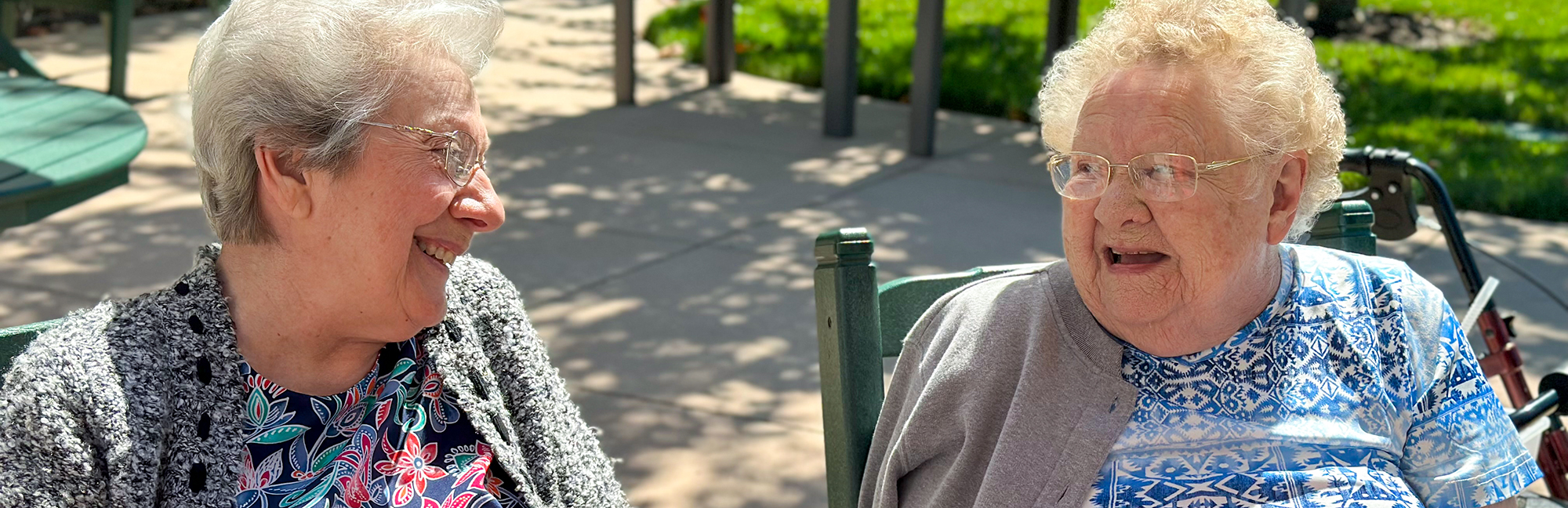 two older women are sitting in chairs talking to each other
