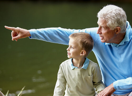 a grandfather points at something while his grandson looks on
