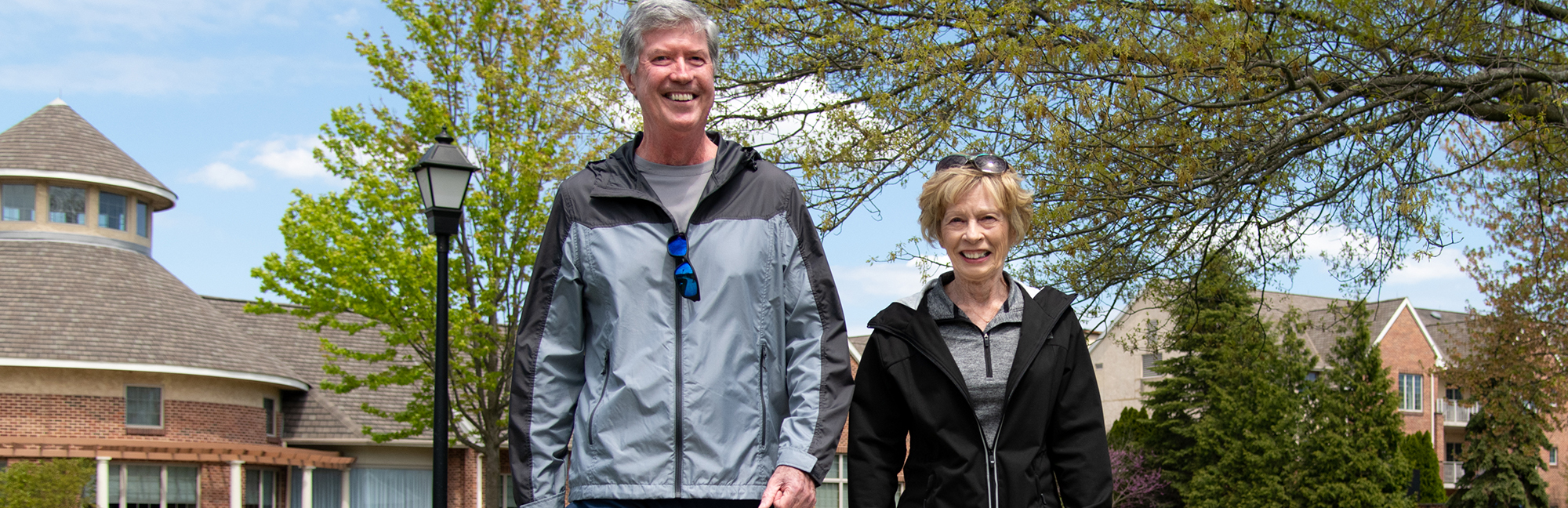 an older man and woman are walking in a retirement community
