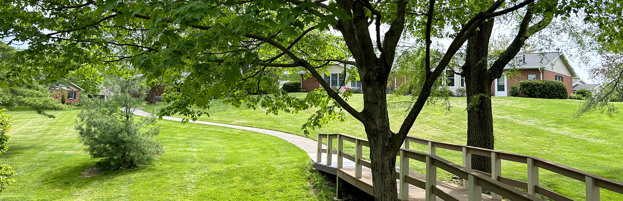 a wooden bridge over a stream with a house in the background