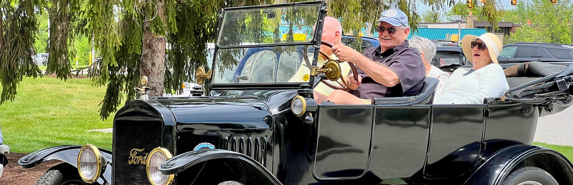a group of retired men and women are sitting in a vintage black ford car
