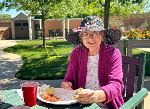 Lady with a sunhat sitting outside eating