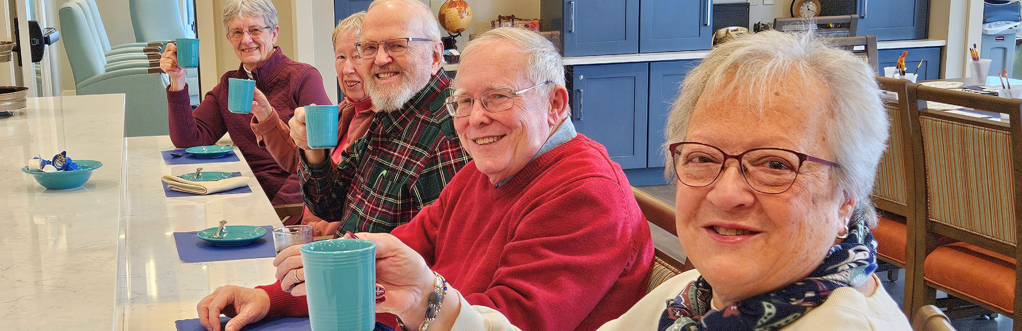 a group of elderly people are sitting at a table drinking coffee