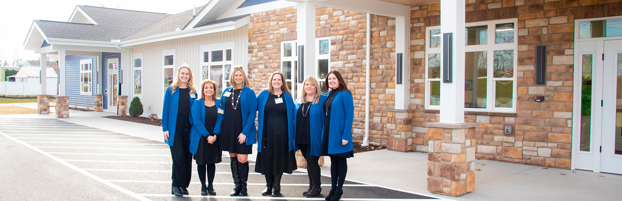 a group of women standing in front of a stone building