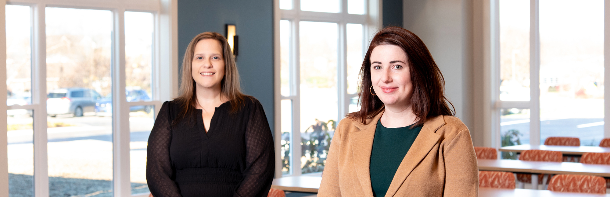 two women standing next to each other in front of a window