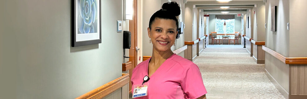 nurse in pink scrubs standing in empty hallway