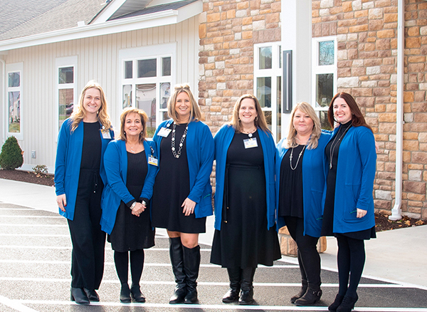 a group of women standing in front of a stone building