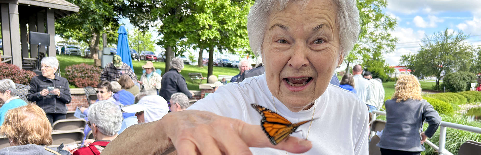 an elderly woman is holding a butterfly on her finger