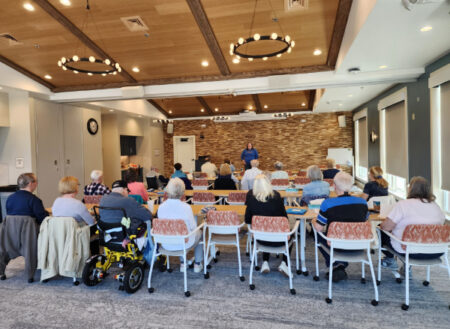 Group of elderly people sitting at tables listening to a speaker